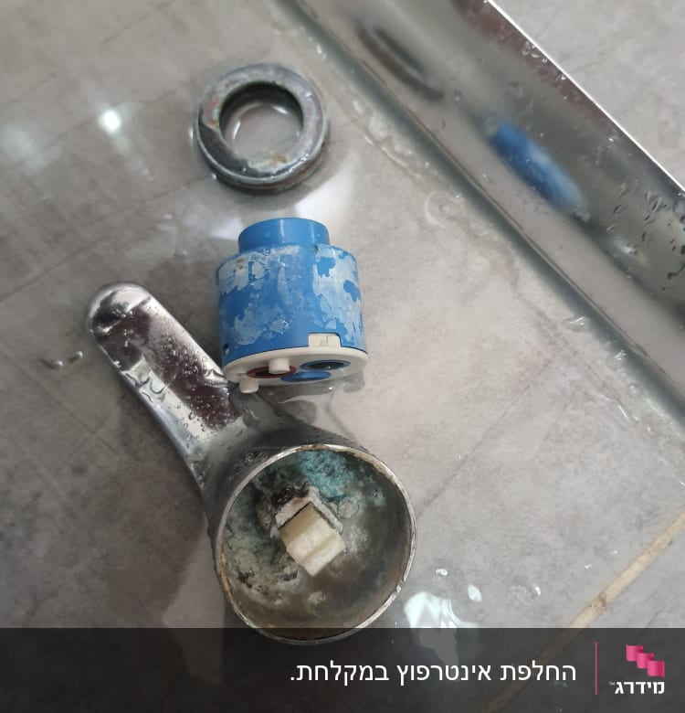 חלקי ברז מפורקים על רצפה רטובה